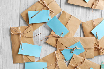 Brown envelopes with tags on wooden background, top view. Mail service