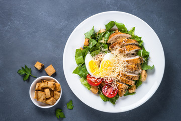 Caesar salad with chicken breast and tomatoes.