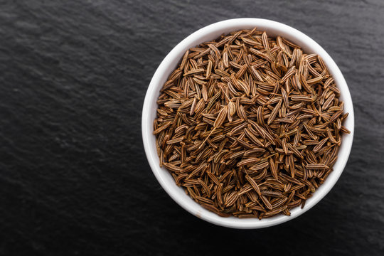 Seeds of cumin on a dark stone background