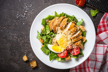 Caesar salad with chicken breast and tomatoes.