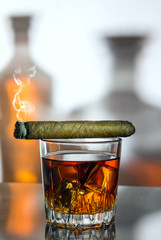 A glass of whiskey and a smoke cigar