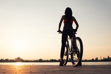 Obraz premium Silhouette of a girl near sea on the bike. Sport and active life concept