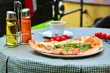 Italian pizza and a cup of coffee on a table of a cuisine