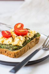 Scrambled eggs on whole wheat bread with avocado and cherry tomatoes