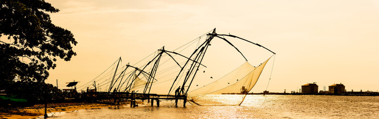 Panoramic silhouette of chinese fishnets on sunset at Fort Kochi, Kerala, India.