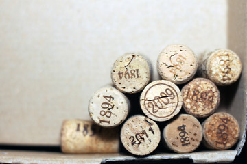 Used wine corks from various varieties of vintage red wine and vintage white wine depicting different dates and years of wine making or creating winery on brown paper background from wine box