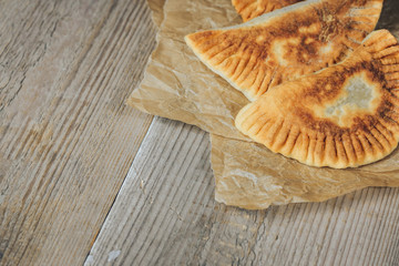 Homemade baking. Chebureks with meat and onion on wooden background.