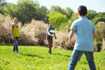 Obraz premium Our activity. Joyful bearded daddy smiling while playing a game with his son and wife