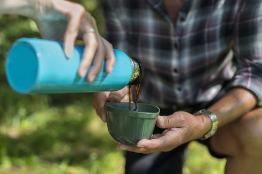 Young woman pouring drink from insulated drink container