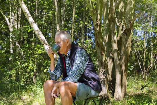 Man drinking from cup in forest