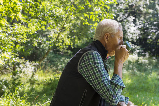 Man drinking from cup in forest