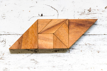 Tangram puzzle in parallelogram shape on old white wood background