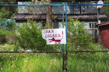 Obraz premium a sign on the fence with a funny picture and an inscription in Russian: Angry dog.