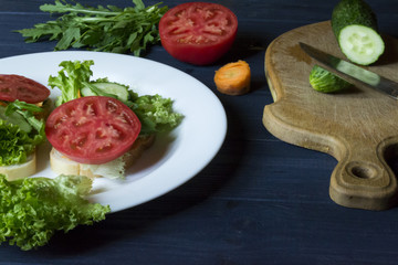 The sandwiches with vegetables on the plate. Vegetarian food. Ingredients for cooking on the table.