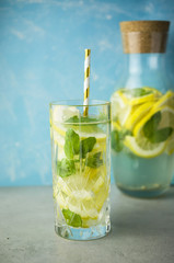Fresh lemonade drink with mint leaves in jar on turquoise background.
