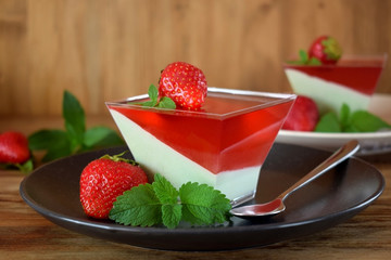 Two layered dessert panna cotta with matcha tea and strawberry jelly in a square bowl