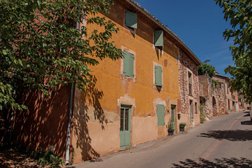 Fototapeta premium Traditional colorful houses in ocher and blue sky in the historic city center of Roussillon. In the Vaucluse department, Provence region, southeastern France.