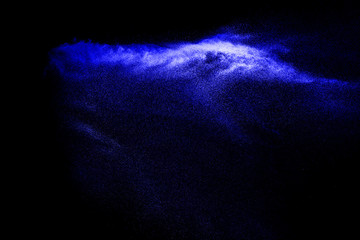 Naklejka na ściany i meble Blue colored sand explosion isolated on black background. Abstract blue sand cloud. Blue colored sand splash against on dark background. Sandy fly wave in the air.