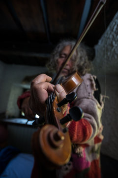 Old artist with dirty nails enjoying his music as he plays a violin