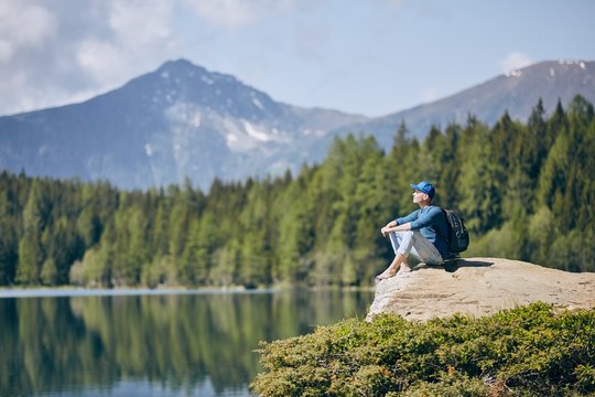 Tourist resting on rock above lake