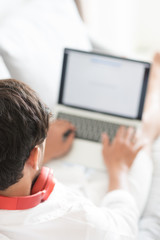 Happy man relaxing on the sofa listening to music with laptop at home