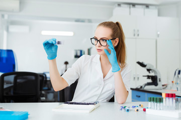 Scientist analyzing microscope slide at laboratory. Female Working in Laboratory With Microscope. Researcher examining slide. Concenrated doctor working with microscope in laboratory