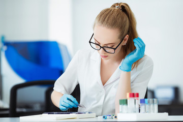 Scientist analyzing microscope slide at laboratory. Female Working in Laboratory With Microscope. Researcher examining slide. Concenrated doctor working with microscope in laboratory