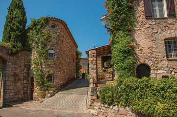 Old stone houses in alley under blue sky, at the gorgeous medieval hamlet of Les Arcs-sur-Argens. Provence region, Var department, southeastern France.