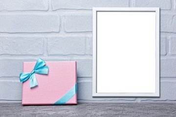 Mock-up of white frame with copy space for poster and pink classic gift box with blue satin bow
