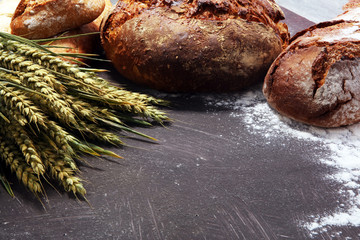 Different kinds of bread and bread rolls on board from above. Kitchen or bakery