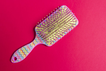 Hairbrush on a pink background. Comb for hair.