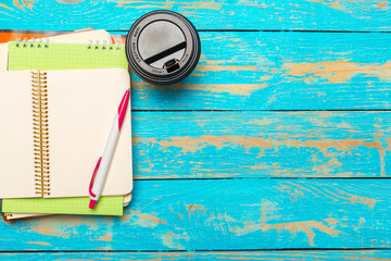 Cup of coffee with notebook on wooden desk