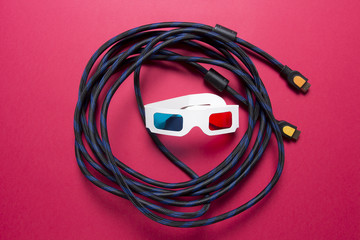 3d Cinema concept through HDMI cable. Watch the movie on 3d TV with HDMI. 3d glasses and hdmi cable on a pink background.
