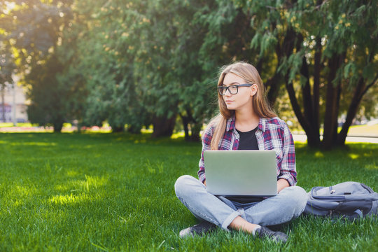 Thoughtful young woman using laptop in park