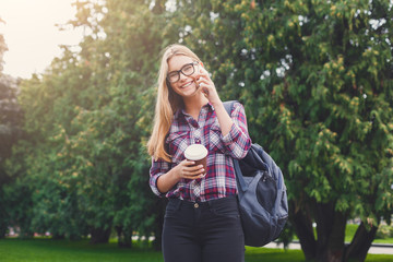 Obraz premium Student girl talking on mobile with coffee cup