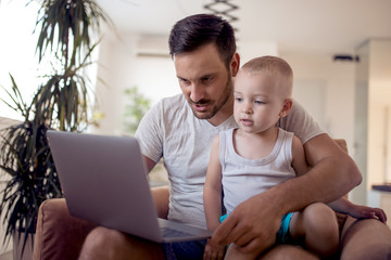 Father and son using laptop at home