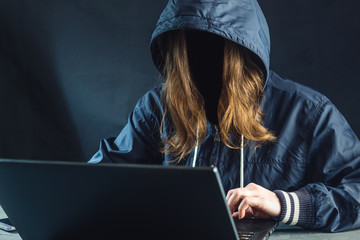 Anonymous girl hacker uses a laptop to hack system. Stealing personal data. Creation and infection...