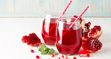 A glass of pomegranate juice with fresh pomegranate fruits on wooden table. Vitamins and minerals. Healthy drink concept.