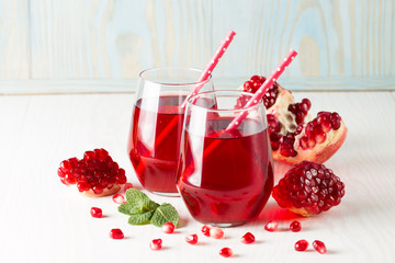 A glass of pomegranate juice with fresh pomegranate fruits on wooden table. Vitamins and minerals. Healthy drink concept.