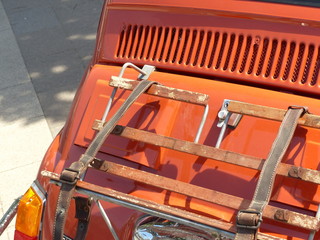 Heckgepäckträger mit Ledergurten eines italienischen Kleinwagen im Orange der Siebziger Jahre bei...