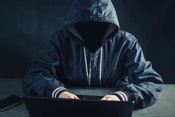 Anonymous hacker programmer uses a laptop to hack the system. Stealing personal data and infection...
