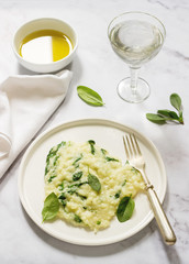 Gentle cream risotto with spinach, served with wine. Light background.