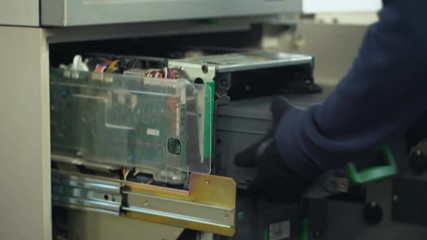 Bank worker replenishing cases of ATM with euro currency, authorized access