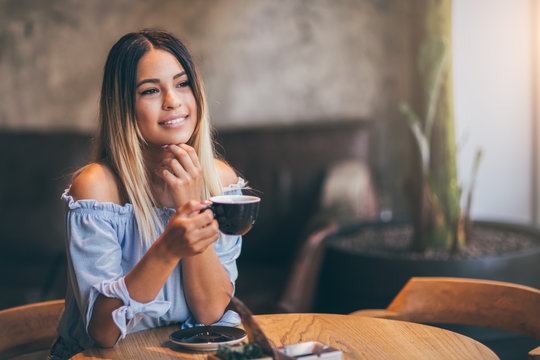 Young hispanic woman at cafe drinking coffee 