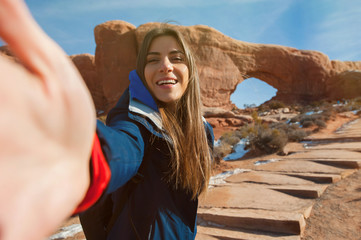 Female traveller taikng self portraits with rock formation in the Arches National Park, Utah, USA