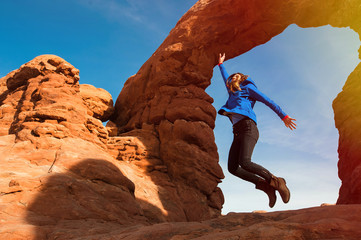 Young woman traveler jumping in the air, hiking the Turret Arch, Arches National Park in Utah © vladteodor