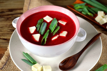 Beet soup-puree topped with bryndza and green onion in a ceramic tureen