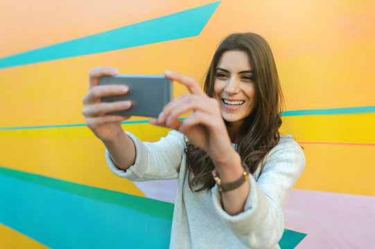 Hipster woman taking selfie photos in colorful abstract background