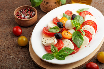 Delicious caprese salad with  tomatoes,mozzarella cheese and fresh basil leaves. Italian food. top view