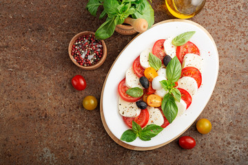 Delicious caprese salad with  tomatoes,mozzarella cheese and fresh basil leaves. Italian food. top view